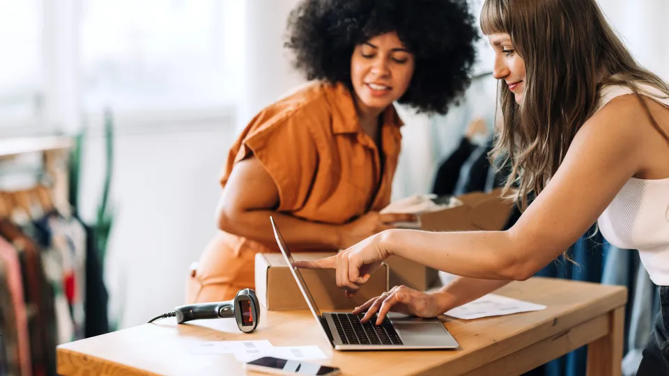 two ecommerce business owners reviewing sales on a laptop